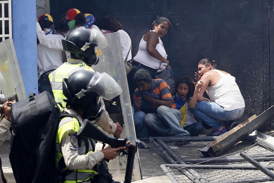 FILE - In this April 19, 2017 file photo, anti-government demonstrators take cover from advancing Bolivarian Police officers during protests in Caracas, Venezuela. “The country is unhappy with the situation right now, and the armed forces are no exception. The military has traditionally been on the right side of history here. If they turn, it's all over for Maduro,” said Cliver Alcala, a retired general who participated in a 1992 coup launched by a then-unknown junior officer named Hugo Chavez. (AP Photo/Ariana Cubillos, File)
