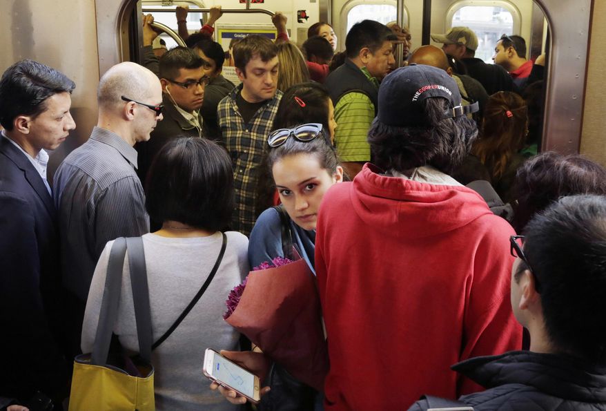 In this May 12, 2016 photo, a woman squeezes between other passengers as she exits a 7 subway train in the Queens borough of New York. It's a wonderful city, where people riding in a hole in the ground have become increasingly frustrated by power outages, signal problems and other delays in the city's 655-mile subway system. (AP Photo/Mark Lennihan)