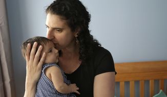 In this Thursday, June 1, 2017 photo Elena Tenenbaum kisses her eight-week-old baby Zoe while standing for a photograph at their home in Providence, R.I. Tenenbaum, a clinical psychology researcher, had her second daughter in April of 2017, and has been able to use Rhode Island&#x27;s paid family leave program, which started in 2014 and covers four weeks of partial pay. (AP Photo/Steven Senne)