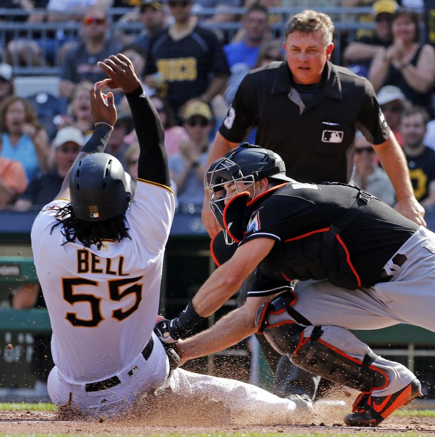 Miami Marlins catcher J.T. Realmuto, right, puts the tag on Pittsburgh Pirates' Josh Bell (55) who was trying to score the second of two runs on a double by Pirates' Andrew McCutchen in the third inning of a baseball game in Pittsburgh, Saturday, June 10, 2017. Umpire Greg Gibson makes the call. (AP Photo/Gene J. Puskar)