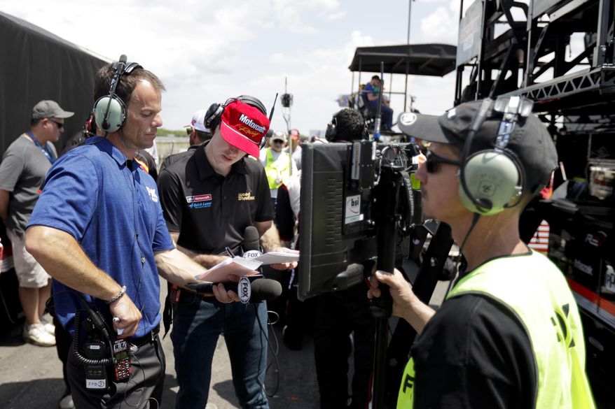 Driver Ryan Blaney, center, and broadcast pit reporter Chris Neville, left, look over notes after a pit stop during the NASCAR xfinity Series auto race, Saturday, June 10, 2017, in Long Pond, Pa. (AP Photo/Matt Slocum)
