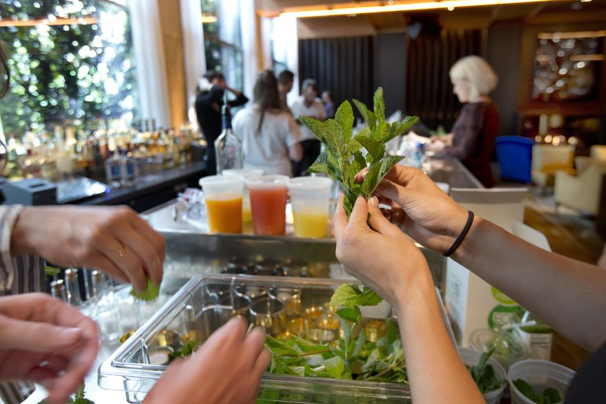 In this June 1, 2017 photo, mint is separated for drinks at the Diego bar at the PUBLIC hotel, in New York. The PUBLIC hotel has a variety of inviting spaces, from bars to tables to big white sofas, where hotel guests, locals and others can socialize, mingle, relax or work. (AP Photo/Richard Drew)