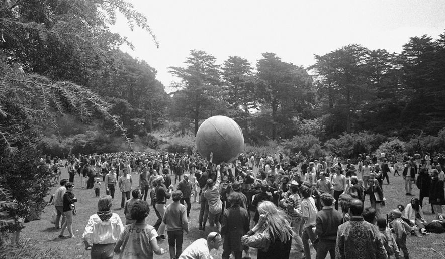 ADVANCE FOR USE TUESDAY, JUNE 13, 2017 AND THEREAFTER-FILE - In this June 21, 1967 file photo, people keep a large ball, painted to represent a world globe, in the air during a gathering at Golden Gate Park in San Francisco, to celebrate the summer solstice on June 21, day one of "Summer of Love." City officials have rejected a permit for a planned free concert intended to mark the 50th anniversary of the famed Summer of Love in Golden Gate Park that had been planned for June 2017. (AP Photo/File)