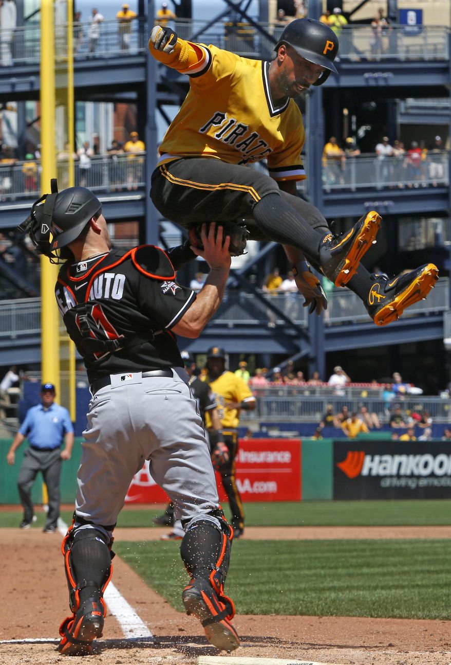 Pittsburgh Pirates' Andrew McCutchen, top, is tagged out by Miami Marlins catcher J.T. Realmuto as he attempts to score on a ground out by Pirates' John Jaso in the sixth inning of a baseball game in Pittsburgh, Sunday, June 11, 2017. (AP Photo/Gene J. Puskar)