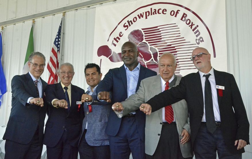 International Boxing Hall of Fame Class of 2017 inductees, from left, Steve Farhood, Barry Tompkins, Marco Antonio Barrera, Evander Holyfield, Jerry Roth and Johnny Lewis display their rings following the induction ceremony in Canastota, N.Y., Sunday, June 11, 2017. (Kyle Mennig/Oneida Daily Dispatch via AP)