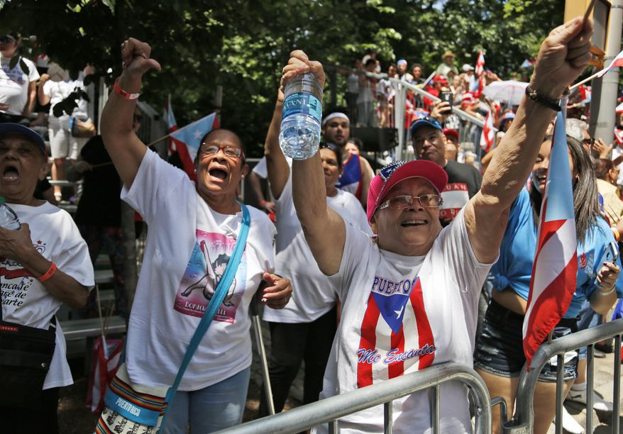 One woman celebrates as another gives a thumbs down as a float carrying Oscar Lopez Rivera passes during the Puerto Rican Day Parade in New York, Sunday, June 11, 2017. Lopez Rivera, former member of the militant Puerto Rican nationalist group Armed Forces of National Liberation, or FALN, was cheered and booed as he stood proudly on a float when the Puerto Rican Day Parade stepped off Sunday. (AP Photo/Seth Wenig)
