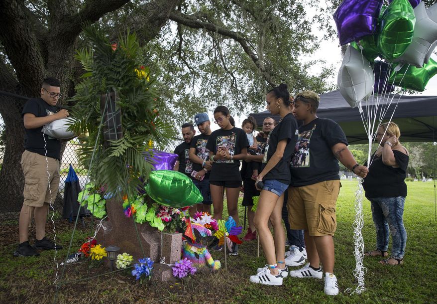 Loved ones of Leroy Valentin Fernandez, one of the victims of the Pulse nightclub shooting, celebrate his life at his grave at Greenwood Cemetery in Orlando, Fla., Monday, June 12, 2017. A gunman opened fire at the nightclub one year ago in the worst mass shooting in modern U.S. history, killing 49 people. (Loren Elliott/Tampa Bay Times via AP)