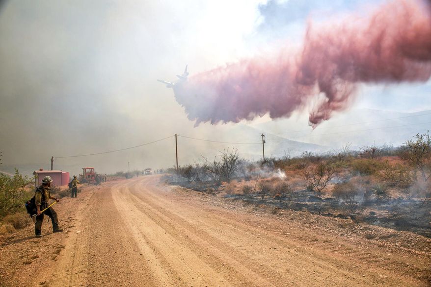 This photo provided by Wyoming Hot Shots, members of the Wyoming Hot Shots firefighting watch a retardant drop while battling the Lizard Fire near Willcox, Ariz., June 10, 2017. Thousands of firefighters continue to battle almost 30 wildfires burning throughout Arizona as gusty winds and dried vegetation continue to fuel the blazes. (Kyle Miller/Wyoming Hot Shots via AP)