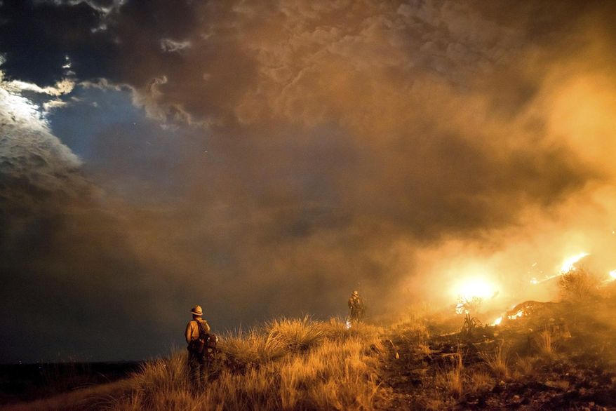 This photo provided by the Wyoming Hot Shots, members of the Wyoming Hot Shots firefighting crew watch the moon break through smoke and clouds while battling the Lizard Fire near Willcox, Ariz., June 8, 2017. Thousands of firefighters continue to battle almost 30 wildfires burning throughout Arizona as gusty winds and dried vegetation continue to fuel the blazes. (Kyle Miller/Wyoming Hot Shots via AP)