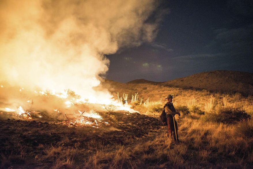 This photo provided by Wyoming Hot Shots, a member of the Wyoming Hot Shots firefighting crew pauses while battling the Lizard Fire near Willcox, Ariz., June 8, 2017. Thousands of firefighters continue to battle almost 30 wildfires burning throughout Arizona as gusty winds and dried vegetation continue to fuel the blazes. (Kyle Miller/Wyoming Hot Shots via AP)