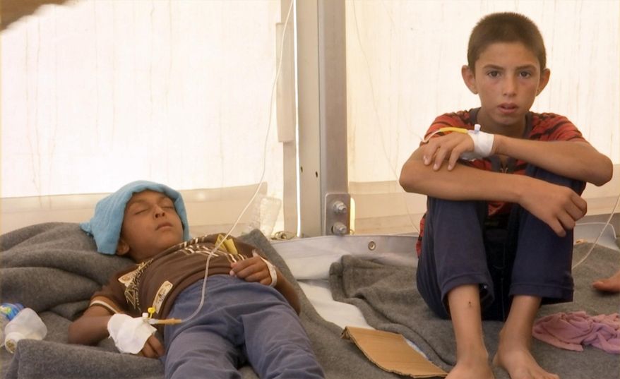 In this frame grab from video, a boy and his brother receive treatment for suspected food poisoning at a medical tent in the Hassan Sham U2 camp for displaced people located about 20 kilometers (13 miles) east of Mosul, Iraq, Tuesday, June 13, 2017. Iraq’s health minister, Adila Hamoud, told The Associated Press in Baghdad that 752 people had been taken ill and at least two died after they took part in a Monday night meal to break the Muslim dawn-to-dusk fasting during the holy month of Ramadan. (AP Photo/Balint Szlanko)