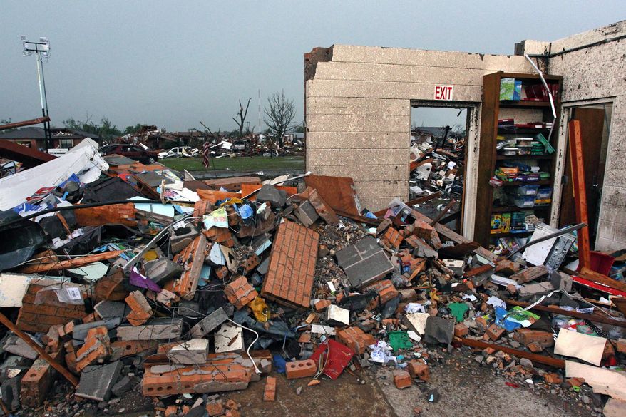 FILE - In this May 23, 2013 file photo, part of a wall stands amid the wreckage of Plaza Towers Elementary School, where seven children were killed when a tornado hit Moore, Okla. The Moore public school system has reached an agreement with the families of the seven children ending three years of litigation. Moore Public Schools said Monday, June 12, 2017 that the families have agreed to accept $14,000 each to settle the lawsuit. (AP Photo/Brennan Linsley File)