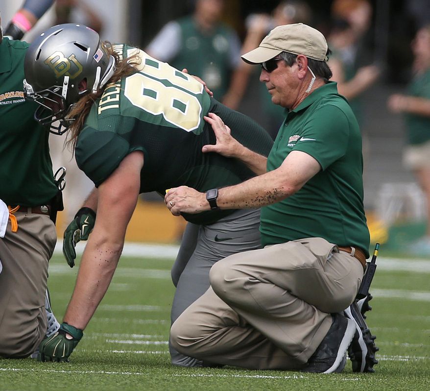 ADVANCE FOR USE MONDAY, JUNE 19 - In this Dec. 3, 2016 photo, Baylor athletic trainer Mike Sims, right, attends to Sam Tecklenburg during an NCAA college football game in Waco, Texas. Sims announced he will leave Baylor after 42 years on staff. He worked 476 consecutive Baylor football games under eight head coaches. (Jerry Larson/Waco Tribune-Herald via AP)