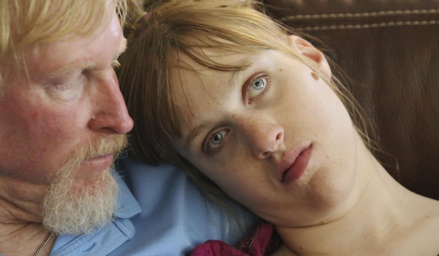This June 6, 2017, photo, Utah resident Doug Rice, hold his daughter Ashley, 24, following a seizure at their home in West Jordan, Utah. Utah lawmakers balked again this year at joining more than half of all U.S. states and passing a broad medical marijuana law. Rice says Utah's approach means his daughter, who has a genetic condition, is missing out on the one drug that eliminates her frequent seizures. (AP Photo/Rick Bowmer)
