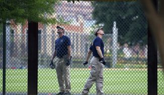 A FBI lab team looks for evidence in the outfield signage at the ball field which is the scene of a multiple shooting in Alexandria, Va., Wednesday, June 14, 2017, after a rifle-wielding attacker opened fire on Republican lawmakers at a congressional baseball practice, wounding House GOP Whip Steve Scalise of Louisiana and several others as congressmen and aides dove for cover. (AP Photo/Cliff Owen)