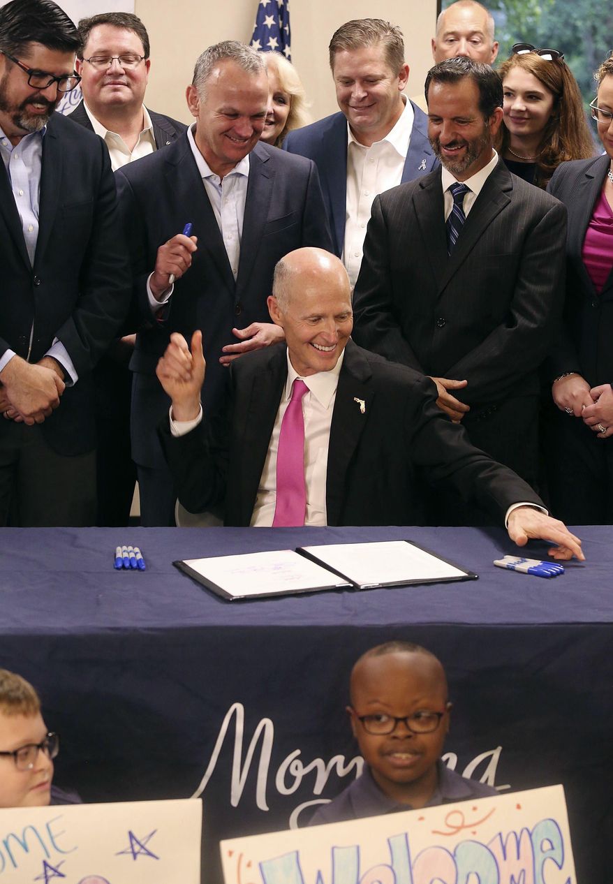 Governor Rick Scott signs a controversial education bill at Morning Star Catholic School, a special needs school, in Orlando on Thursday, June 15, 2017. (Stephen M. Dowell /Orlando Sentinel via AP)
