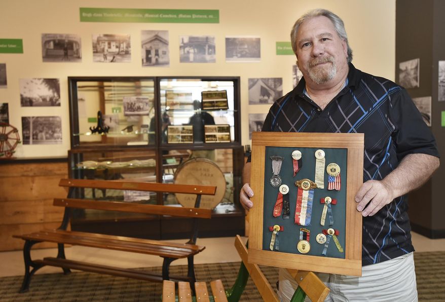 D&L volunteer and Island Park historian Bob Pasquini holds ribbons that were given to visitors to the park as he stands near on an actual park bench once used in the park on June 8, 2017 in Easton, Pa. Easton Island Park, one of several amusement parks started by local trolley companies to boost weekend fares, was uniquely situated on a 100-acre island in the middle of the Lehigh River, accessible via a trestle built for the trolley. Researchers hope a new exhibit at the National Canal Museum might elicit more information and memorabilia. (April Bartholomew/The Morning Call via AP)