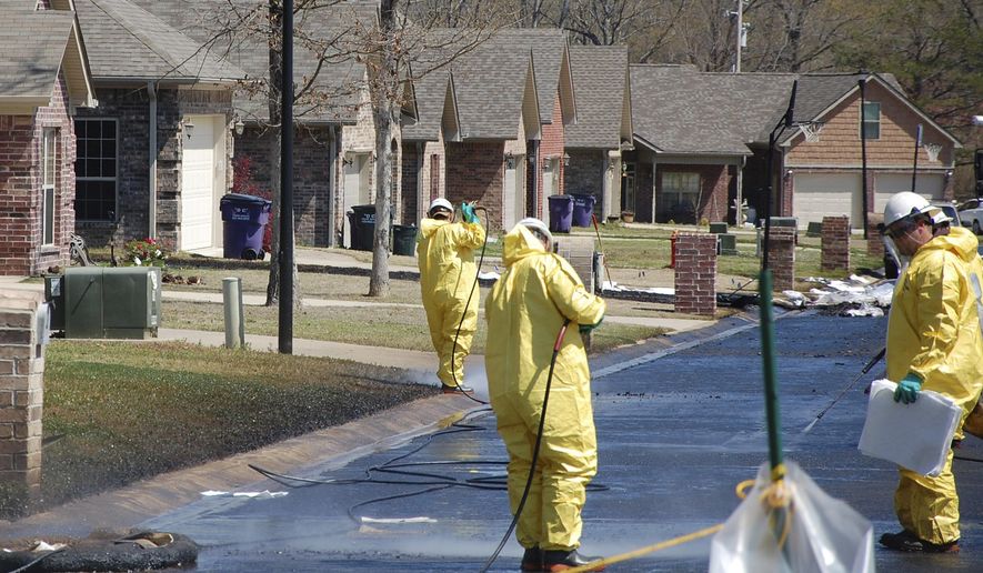 FILE - In this April 1, 2013, file photo, crews work to clean up oil in a Mayflower, Ark., neighborhood after an oil pipeline ruptured and spewed oil over lawns and roadways. A settlement has been reached for families affected by the 2013 Exxon Mobil oil spill in central Arkansas. Attorneys for the residents and homeowners announced the settlement Thursday, June 15, 2017. They say terms will remain confidential. (AP Photo/Jeannie Nuss, File)