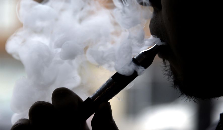 FILE - In this April 23, 2014 file photo, a man smokes an electronic cigarette in Chicago. A large government survey released Thursday, June 15, 2017, suggests the number of U.S. high school and middle school students using electronic cigarettes fell to 2.2 million last year, from 3 million the year before. (AP Photo/Nam Y. Huh, File)