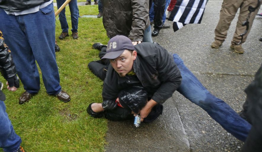 A person protesting with the conservative group Patriot Prayer, top, detains a counter-protester who had been involved in an altercation with the group before other members of the group dragged the counter-protester to Washington State Troopers, Thursday, June 15, 2017, at Evergreen State College in Olympia, Wash. (AP Photo/Ted S. Warren)