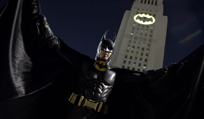 A man poses in front of a Bat-Signal projected onto City Hall at a tribute to &amp;quot;Batman&amp;quot; star Adam West on Thursday, June 15, 2017, in Los Angeles. (Photo by Chris Pizzello/Invision/AP) **FILE**