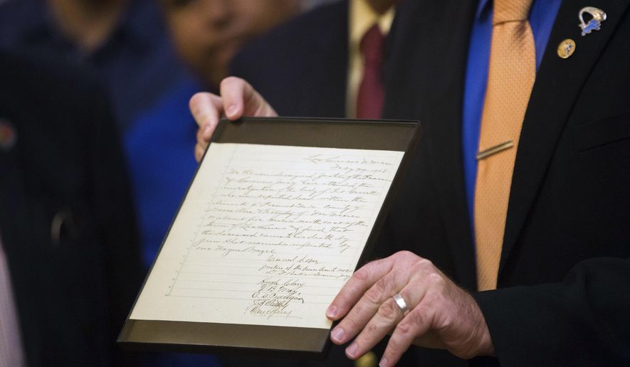 Scott Krahling, Doña Ana County Clerk, holds up Pat Garrett's corners report, Friday, June 16, 2017, at an unveiling ceremony of the law mans coroners report, at the Doña Ana County Government Center. (Josh Bachman /The Las Cruces Sun-News via AP)