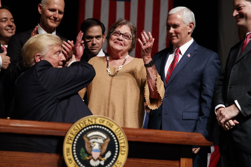 Cuban dissident Cary Roque is handed a pen by President Donald Trump after he signed an executive order on Cuba policy, Friday, June 16, 2017, in Miami. From left are, Florida Gov. Rick Scott, Sen. Marco Rubio, R-Fla., Roque, Vice President Mike Pence and Labor Secretary Alex Acosta. (AP Photo/Evan Vucci)