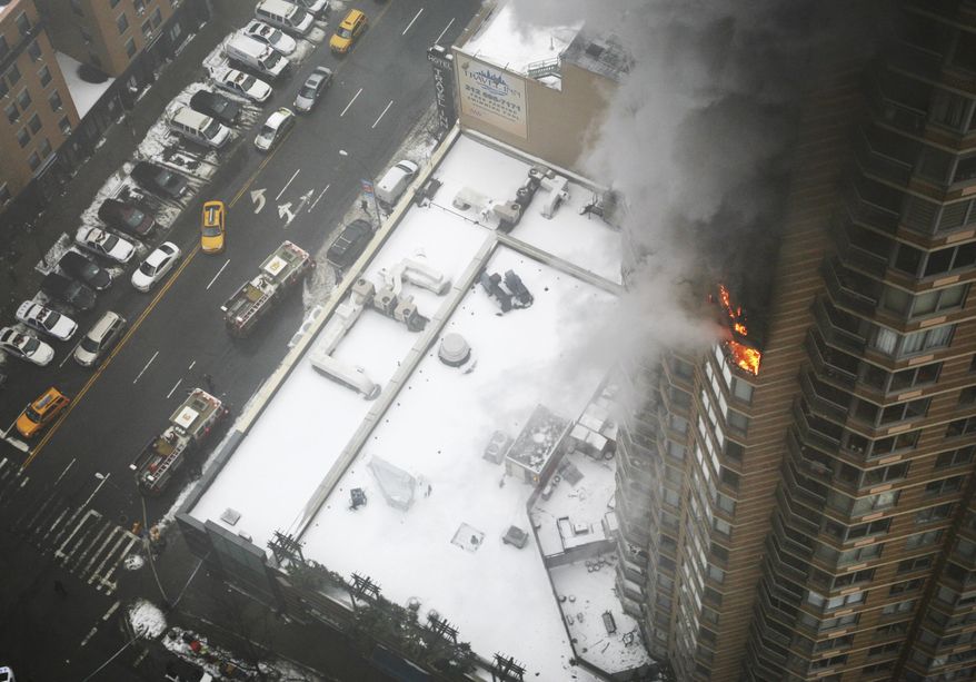 FILE- In this Jan. 5, 2014 file photo, flames and smoke emerge from the 20th floor of the Strand apartment building near Times Square in New York. Fire safety experts say despite that outcome, "stay put" is still the best advice if fire breaks out in a different part of a high rise building. The recommend sheltering in place as long as the building has proper fire suppression protections, like a sprinkler system, fireproof doors and flame-resistant construction materials. (AP Photo/Katherine Bourbeau, File)