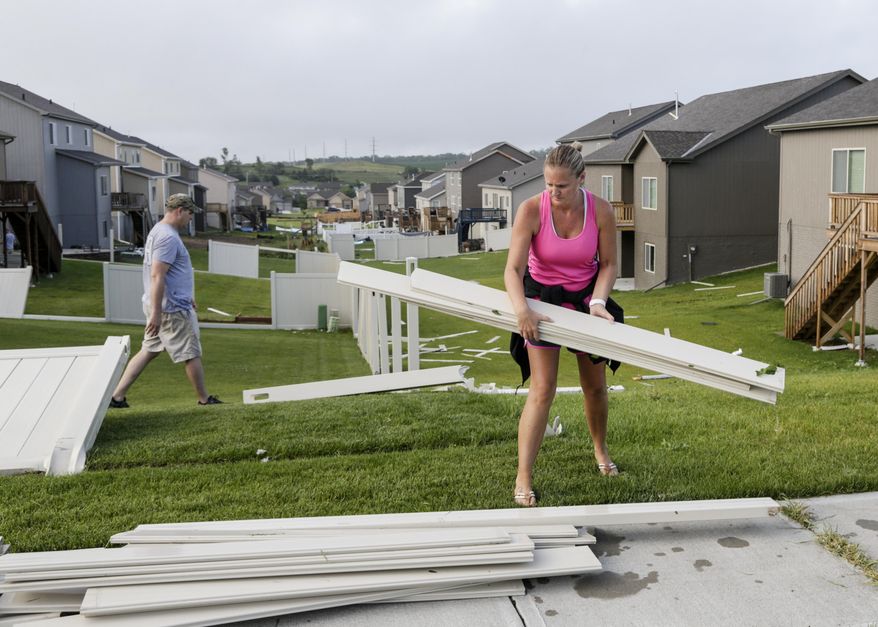 Ashley Peterson and her husband Jason, clear debris around their weather damaged home in the Hyda Hills neighborhood in Bellevue, Neb., Saturday, June 17, 2017. A severe weather front passed through the area the previous evening. (AP Photo/Nati Harnik)