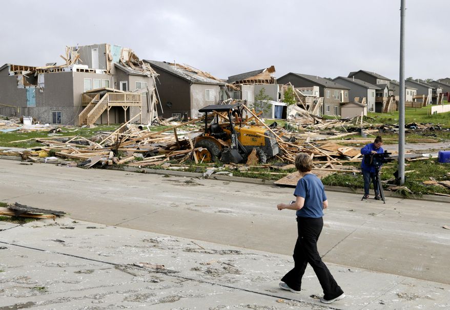 A neighbor walks past damaged homes in the Hyda Hills neighborhood in Bellevue, Neb., Saturday, June 17, 2017. A severe weather front passed through the area the previous evening. (AP Photo/Nati Harnik)