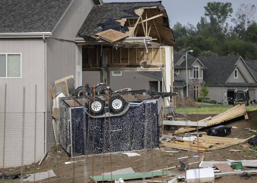 An overturned trailer comes to rest against a storm-damaged home in the Hyda Hills neighborhood in Bellevue, Neb., Saturday, June 17, 2017. A severe weather front passed through the area the previous evening. (AP Photo/Nati Harnik)
