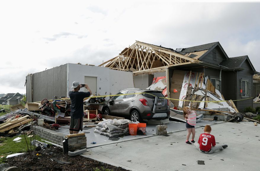 A neighbor and grand children of absent homeowners are seen in front of a weather-damaged home in the Hyda Hills neighborhood in Bellevue, Neb., Saturday, June 17, 2017. A severe weather front passed through the area the previous evening. (AP Photo/Nati Harnik)