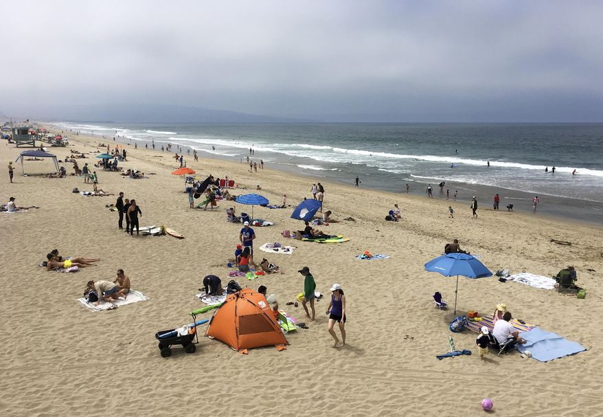 People enjoy the cooler weather in Manhattan Beach, Calif., Sunday, June 18, 2017. Skies cleared intermittently and then a steady onshore breeze kept the marine layer pressed against the shoreline. Almost all of inland California was predicted to simmer this week at above normal temperatures. The National Weather Service has warned those spending time outside to, when possible, reschedule strenuous activities to early morning or evening. (AP Photo/John Antczak)