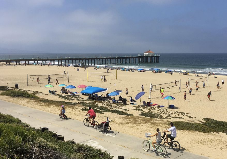 People enjoy the cooler weather in Manhattan Beach, Calif., Sunday, June 18, 2017. Skies cleared intermittently and then a steady onshore breeze kept the marine layer pressed against the shoreline. Almost all of inland California was predicted to simmer this week at above normal temperatures. The National Weather Service has warned those spending time outside to, when possible, reschedule strenuous activities to early morning or evening. (AP Photo/John Antczak)