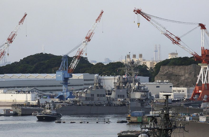 The damaged USS Fitzgerald, center, arrives at the U.S. Naval base in Yokosuka, southwest of Tokyo, after the U.S. destroyer collided with the Philippine-registered container ship ACX Crystal in the waters off the Izu Peninsula Saturday, June 17, 2017. The USS Fitzgerald was back at its home port in Japan after colliding before dawn Saturday with the ACX Crystal four times its size, while the coast guard and Japanese and U.S. military searched for seven sailors missing after the crash. (AP Photo/Eugene Hoshiko)