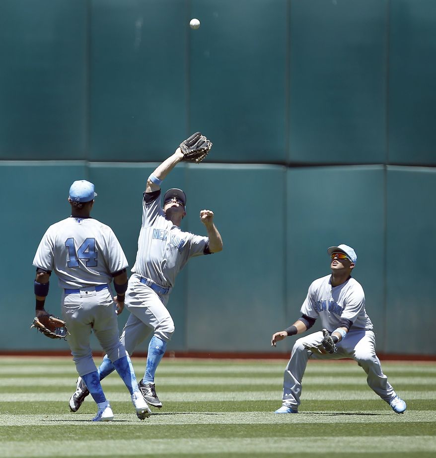 New York Yankees left fielder Brett Gardner, center, makes a catch on a pop up fly ball between second baseman Starlin Castro (14) and center fielder Mason Williams, right, during the second inning against the Oakland Athletics in a baseball game on Sunday, June 18, 2017 in Oakland, Calif. (AP Photo/Tony Avelar)