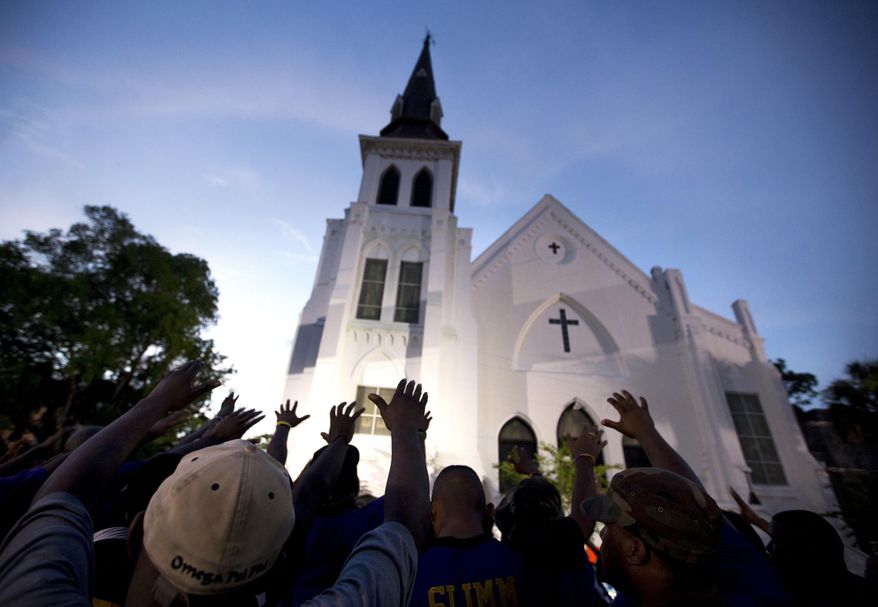 In this June 19, 2015, file photo, the men of Omega Psi Phi Fraternity Inc. lead a crowd of people in prayer outside the Emanuel AME Church, after a memorial for the nine people killed by Dylann Roof in Charleston, S.C. The pastor of the church is expected to announce the designer of a memorial to the nine people killed in the church's fellowship hall in a racist massacre two years ago Saturday, June 17, 2017. Other ceremonies are also planned to mark the second anniversary of the killings. (AP Photo/Stephen B. Morton, File)
