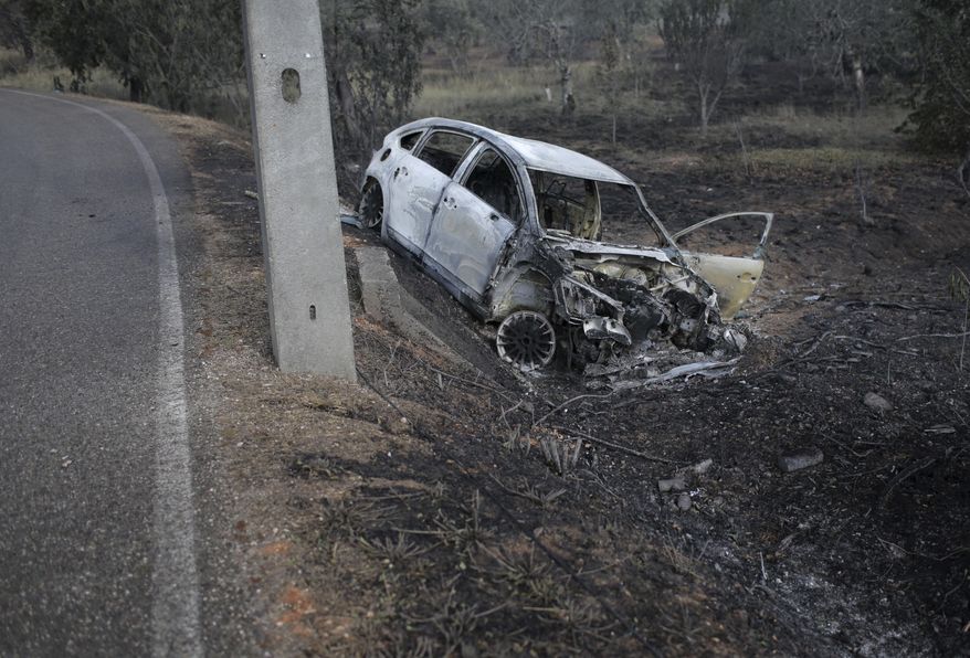 A burnt car lies where it went off the road in the village of Nodeirinho, near Pedrogao Grande, central Portugal, Monday, June 19 2017. At least 11 people were killed in the village Saturday when it was swept by a forest fire. Raging forest fires in central Portugal killed at least 62 people, many of them trapped in their cars as flames swept over roads Saturday evening. (AP Photo/Armando Franca)