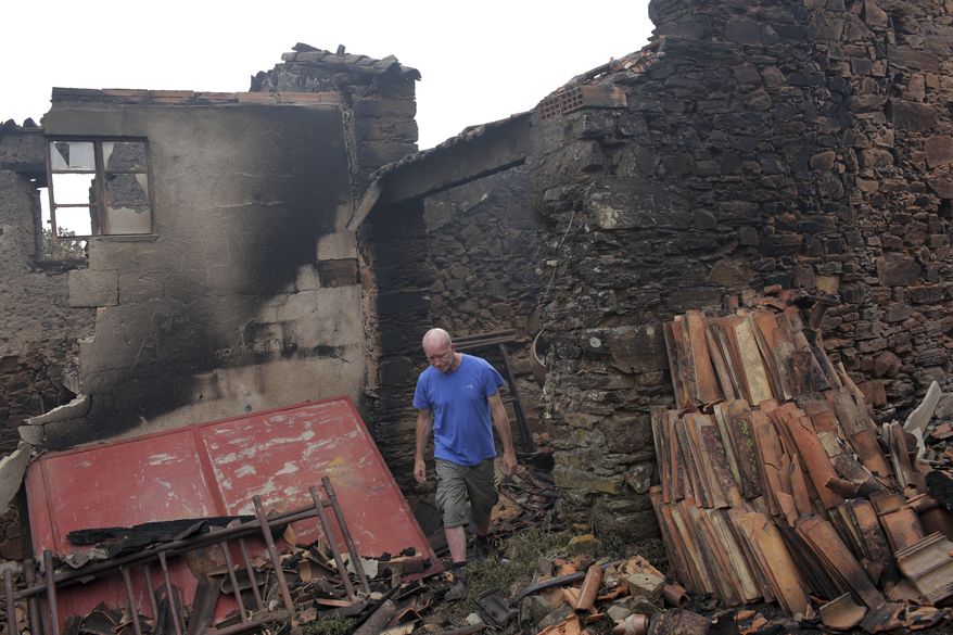 British citizen Daniel Starling walks among the debris of his burnt house in the village of Figueira, near Pedrogao Grande, central Portugal, Monday, June 19 2017.  Raging forest fires in central Portugal killed tens of  people, many of them trapped in their cars as flames swept over roads Saturday evening.  (AP Photo/Armando Franca),