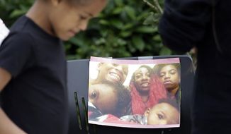 A neighbor girl walks past a memorial outside where a pregnant mother was shot and killed a day earlier at her apartment by police Monday, June 19, 2017, in Seattle. A cousin of a mother who was shot and killed by Seattle police has questioned why officers didn&#39;t use a Taser or other non-lethal options during the encounter. (AP Photo/Elaine Thompson)