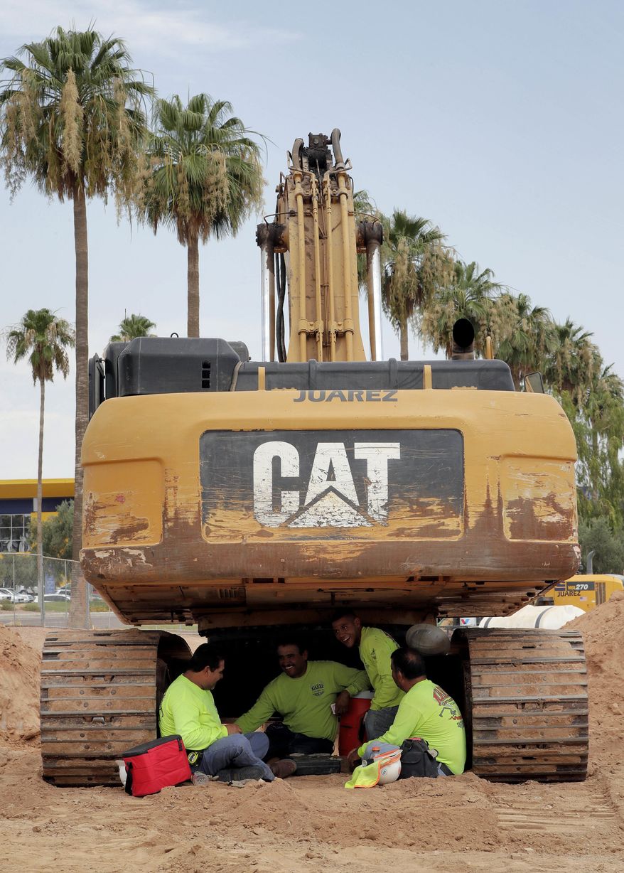 A crew from Juarez Construction sits under their excavator during a break to avoid the heat, Tuesday, June 20, 2017 in Tempe, Ariz. Phoenix hit a high of 118 on Monday with an excessive heat warning in place until Saturday. (AP Photo/Matt York)