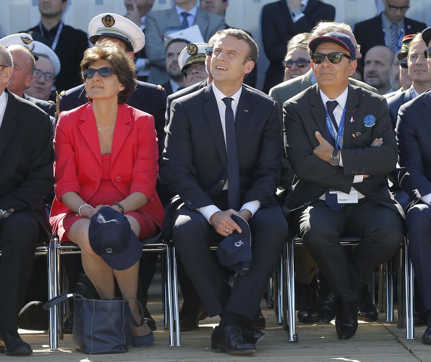 French President Emmanuel Macron, center, French defense minister Sylvie Goulard and Dassault Aviation CEO Eric Trappier, right, watch demonstration flights as part of the Paris Air Show in Le Bourget, north of Paris, Monday, June 19, 2017. Macron landed Monday at the Bourget airfield in an Airbus A400-M military transport plane to launch the aviation showcase, where the latest Boeing and Airbus passenger jets will vie for attention with a F-35 warplane, drones and other and high-tech hardware. (AP Photo/Michel Euler, Pool)