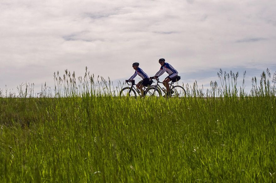 Dave Kummer, left, and Steve Rice, left, and and ride Friday along Highway 59 near Rawhide Creek north of Gillette on bikes they'll pedal all the way to Maine to raise money for Fanconi anemia research. For 40 years, Kummer, 61, said he had wanted to ride across the country, but he didn’t have the time. Then he retired and brought up the idea with his friend Rice, 66, who suggested they do it for charity. They decided to focus on Fanconi anemia, a hereditary disease that affects the bone marrow. (Ed Glazar/Gillette News Record via AP)