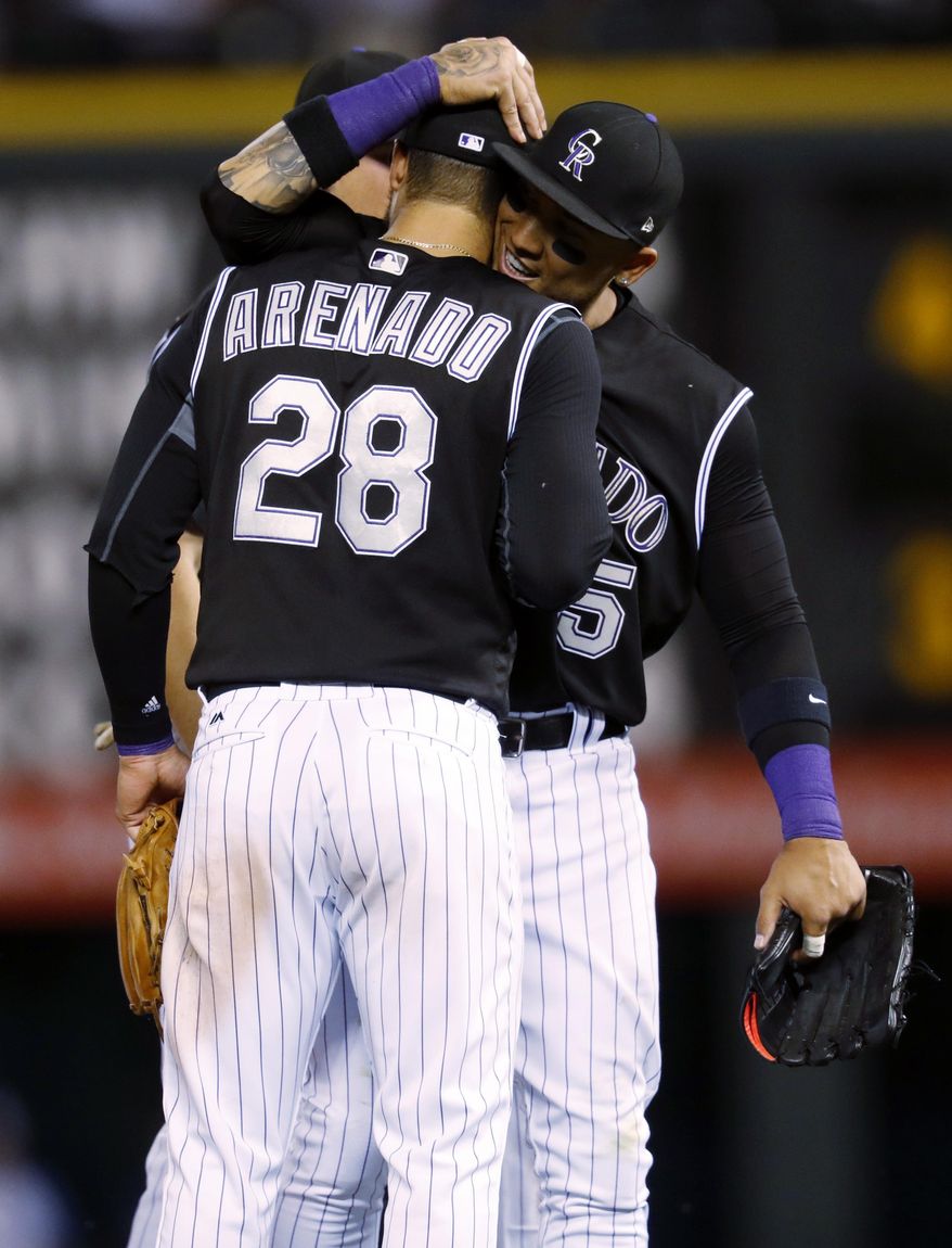 Colorado Rockies third baseman Nolan Arenado, front, is congratulated by right fielder Carlos Gonzalez after the Rockies defeated the Arizona Diamondbacks 4-3 in a baseball game Tuesday, June 20, 2017, in Denver. (AP Photo/David Zalubowski)