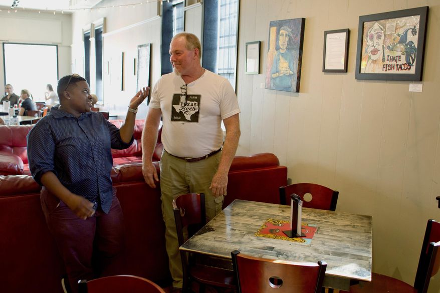 ADVANCE FOR WEEKEND EDITIONS - In this Thursday, June 15, 2017, photo, U.S. Army veteran Erika Land, left, the author of "How to Be a Slam Poet" meets with U.S. Navy veteran Douglas Meredith, the artist behind "How to Be a Slam Poet (I Hate Fish Tacos), a piece created in response to Land's writing at the VSA Texas' 8th annual Distinguished Artist Veterans Exhibit and Showcase at Village Cafe & Art979 Gallery in Downtown Bryan, Texas. (Timothy Hurst/College Station Eagle via AP)