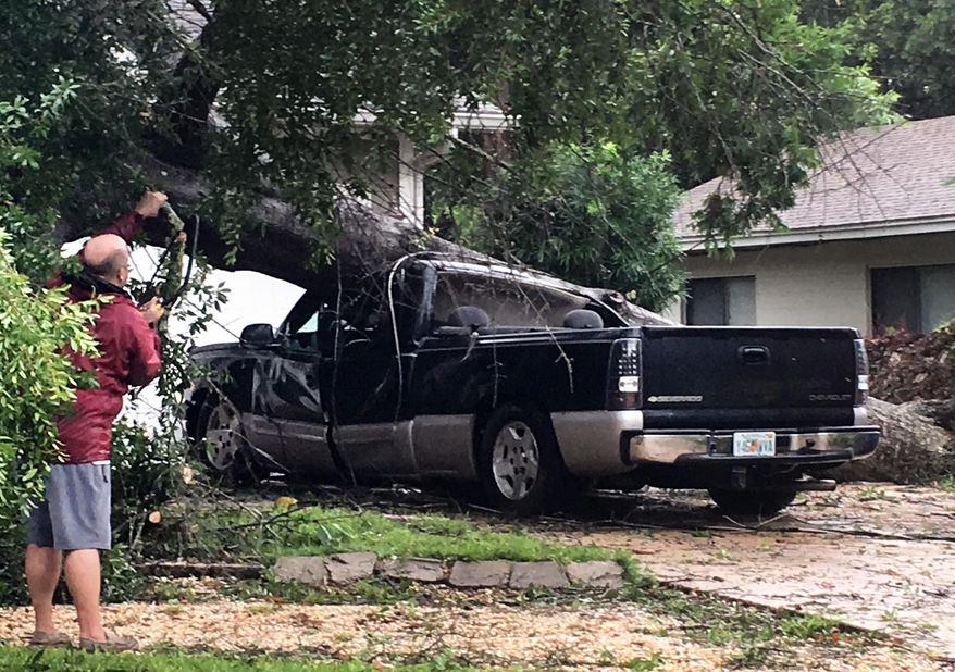 An unidentified man looks at a truck that was crushed by a falling tree in Fort Walton Beach, Florida on Wednesday, June 21, 2017. This Florida panhandle community was hit by a wave of severe weather Wednesday morning as Tropical Storm Cindy churns through the Gulf of Mexico. (Tom Mclaughlin/Northwest Florida Daily News via AP)