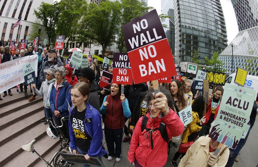 In this May 15, 2017, photo, protesters wave signs and chant during a demonstration against President Donald Trump&#x27;s revised travel ban outside a federal courthouse in Seattle. A federal judge said Wednesday, June 21, 2017, that a class-action lawsuit challenging a once-secret government program that delayed immigration and citizenship applications by Muslims can move forward. (AP Photo/Ted S. Warren, file)