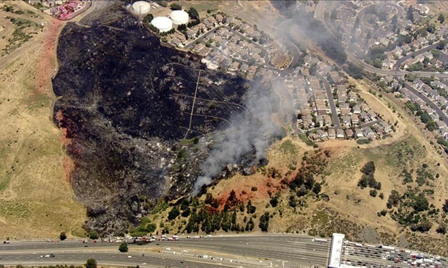 In this image provided courtesy of KTVU-TV, a wildfire burns on a hillside near the Carquinez Bridge Toll Plaza Thursday, June 22, 2017, in Vallejo, Calif. Firefighters have reported that "multiple" homes are burning and others are at risk as they battle a 4-alarm grass fire in Vallejo. The Vallejo Fire Department says the blaze off Interstate 80 near the Carquinez Bridge has led to the closure of all eastbound lanes on I-80. (Courtesy of KTVU-TV via AP)