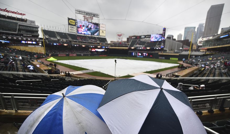 A couple of hardy fans wait out a rain delay under umbrellas before a baseball game between the Minnesota Twins and Chicago White Sox, Thursday, June 22, 2016, in Minneapolis. (AP Photo/John Autey)