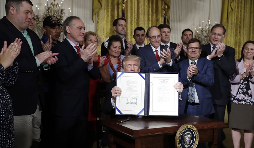 President Donald Trump displays the &quot;Department of Veterans Affairs Accountability and Whistleblower Protection Act of 2017&quot; after signing in the East Room of the White House, Friday, June 23, 2017, in Washington, as Secretary of Veteran Affairs David Shulkin and others look on. (AP Photo/Evan Vucci)